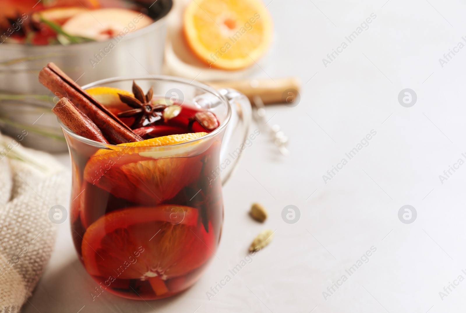 Photo of Glass cup of tasty mulled wine on grey table. Space for text