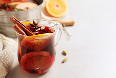 Photo of Glass cup of tasty mulled wine on grey table. Space for text