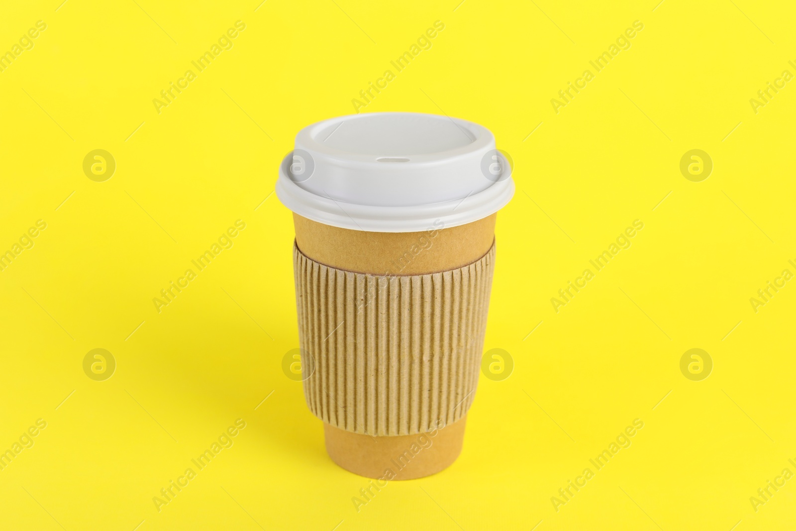 Photo of Paper cup with plastic lid on yellow background. Coffee to go