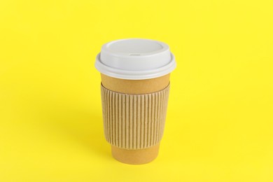 Photo of Paper cup with plastic lid on yellow background. Coffee to go