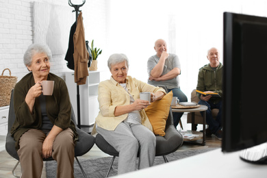 Elderly people watching TV in geriatric hospice. Senior people care