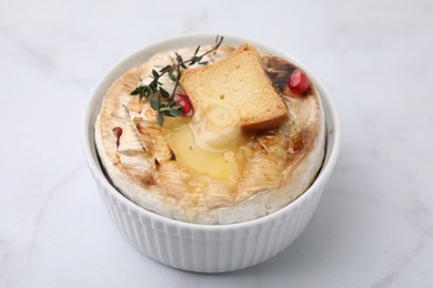 Tasty baked camembert with crouton and thyme on white marble table, closeup