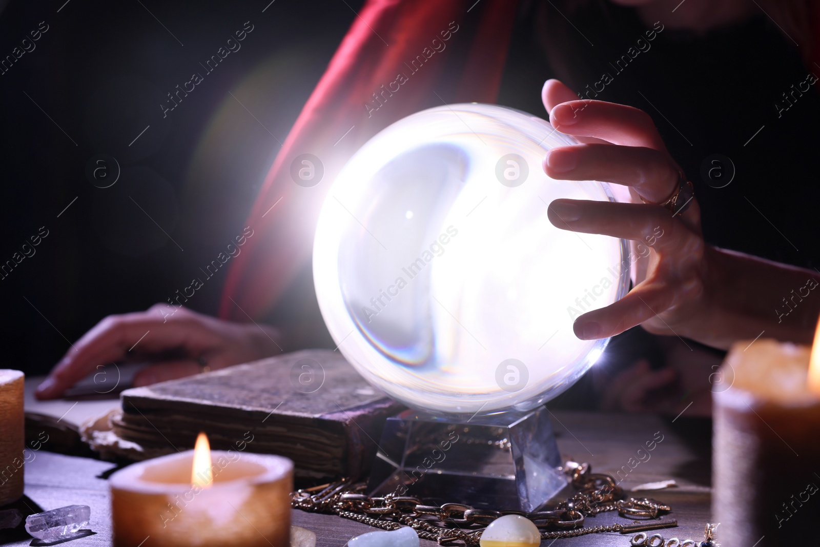 Photo of Soothsayer using crystal ball to predict future at table in darkness, closeup. Fortune telling