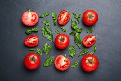 Fresh basil leaves and tomatoes on black slate table, flat lay