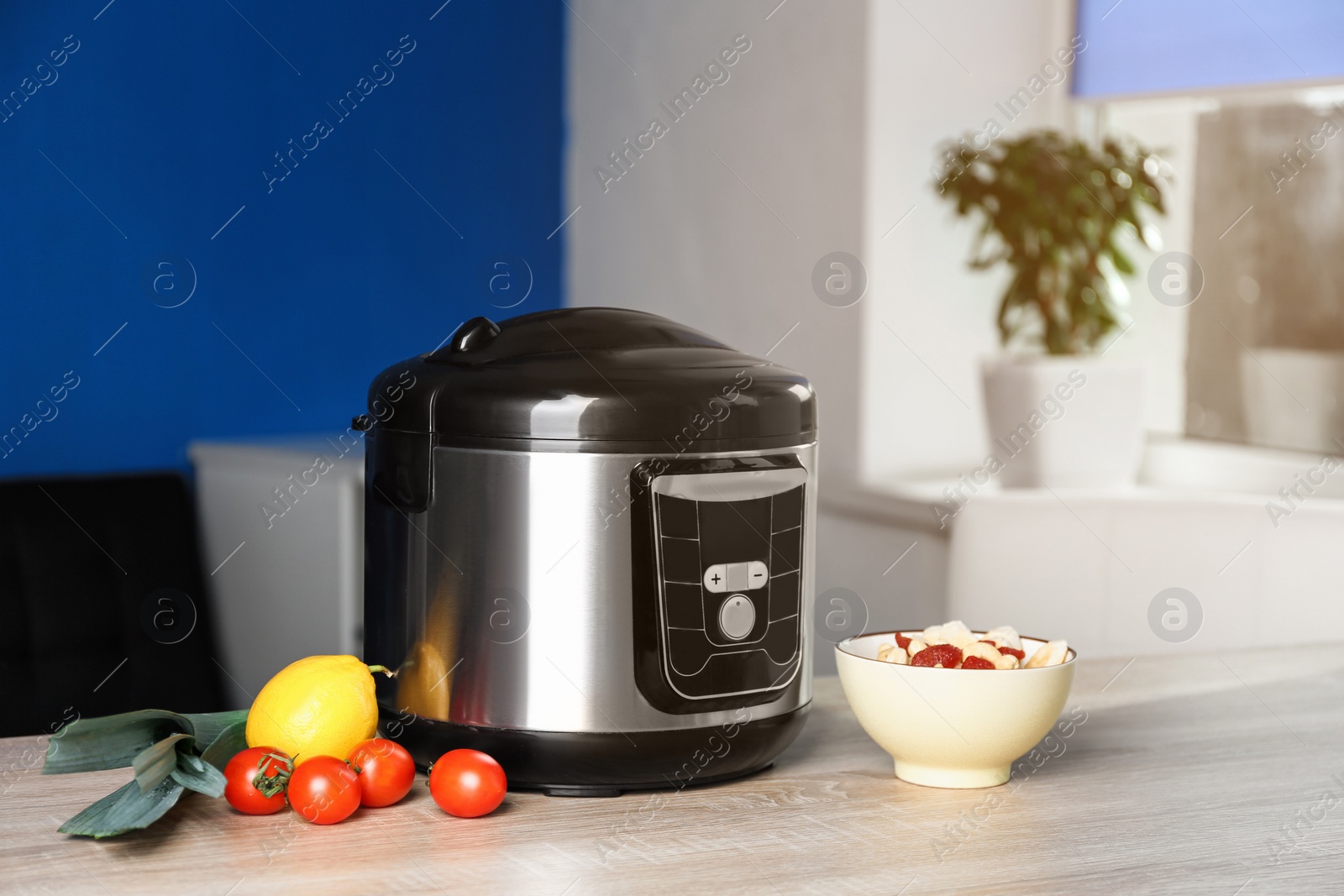 Photo of Modern multi cooker and ingredients on table in kitchen