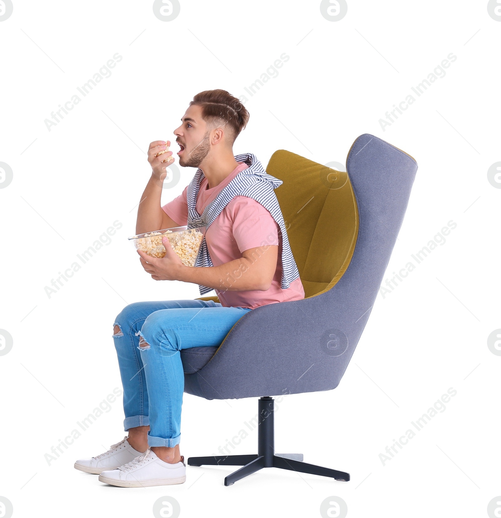 Photo of Handsome young man with bowl of popcorn in armchair on white background. Watching cinema