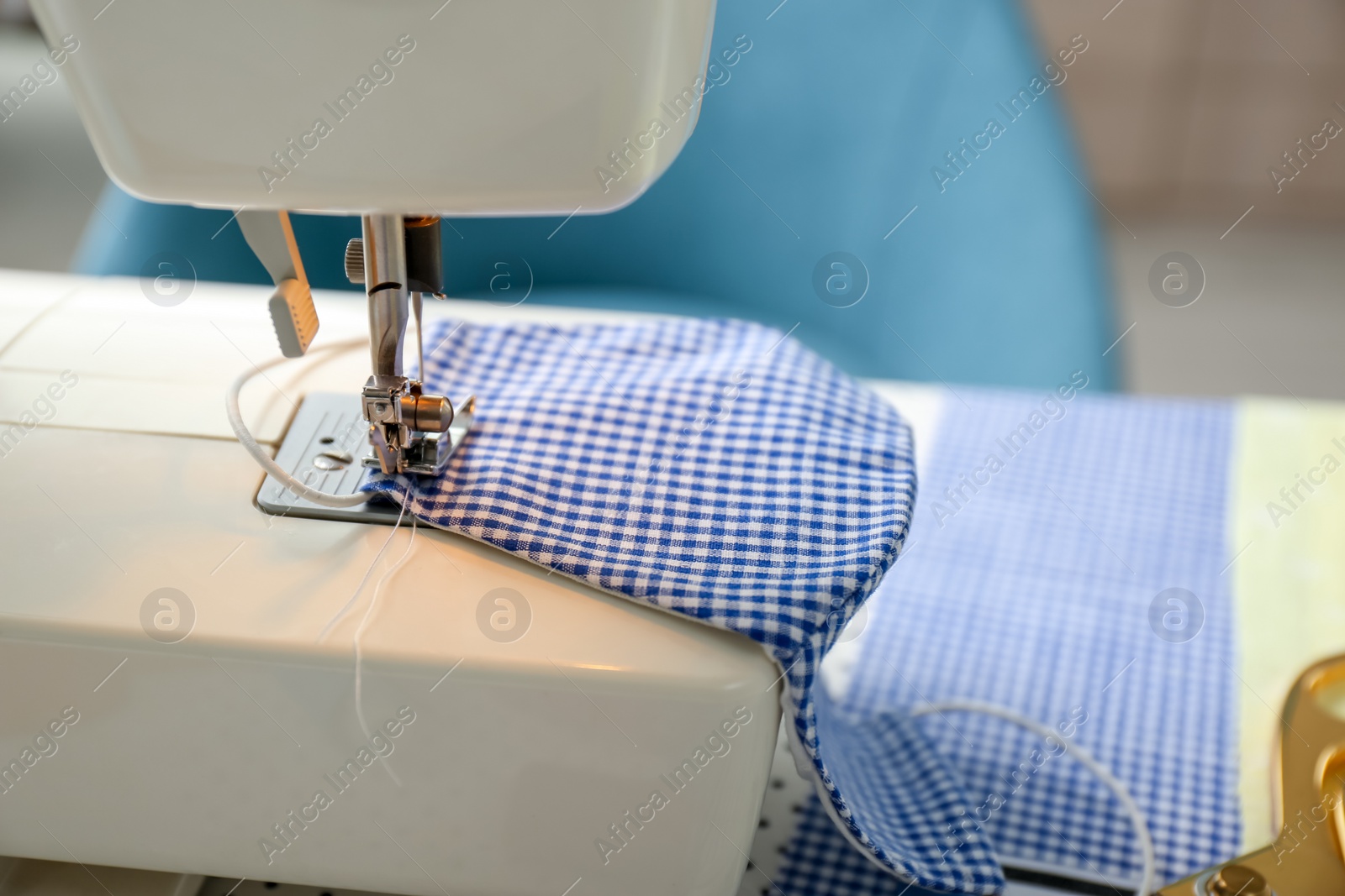 Photo of Sewing machine with cloth mask on table, closeup. Personal protective equipment during COVID-19 pandemic