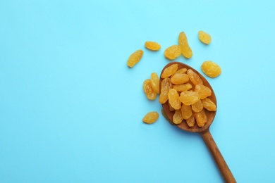 Spoon of raisins on color background, top view with space for text. Dried fruit as healthy snack