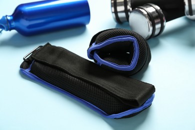 Photo of Weighting agents, dumbbells and sport bottle on light blue background