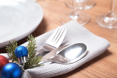 Photo of Cutlery, napkin and Christmas decor on wooden background, closeup. Festive table setting