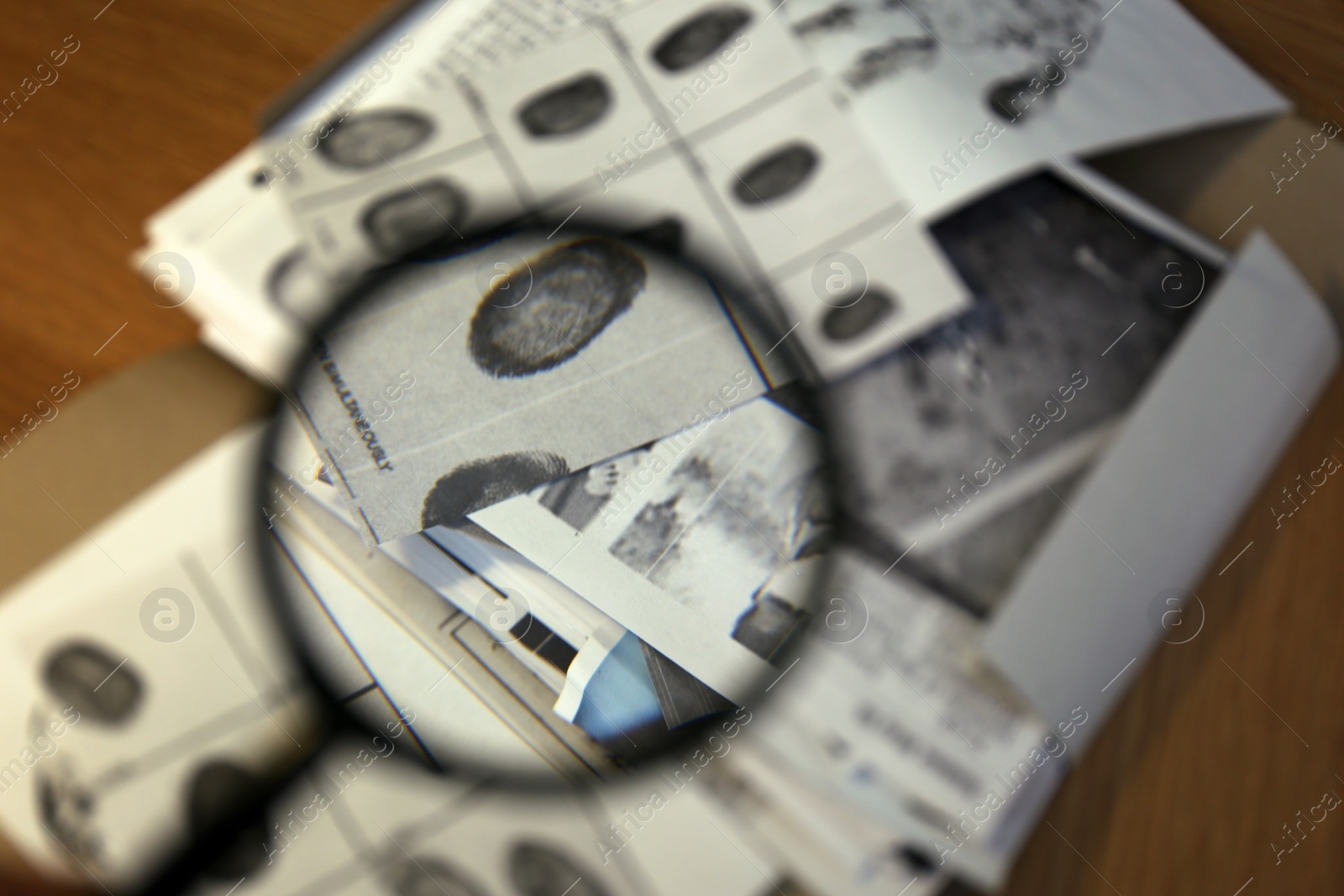 Photo of Fingerprint card on table, view through magnifying glass. Detective work