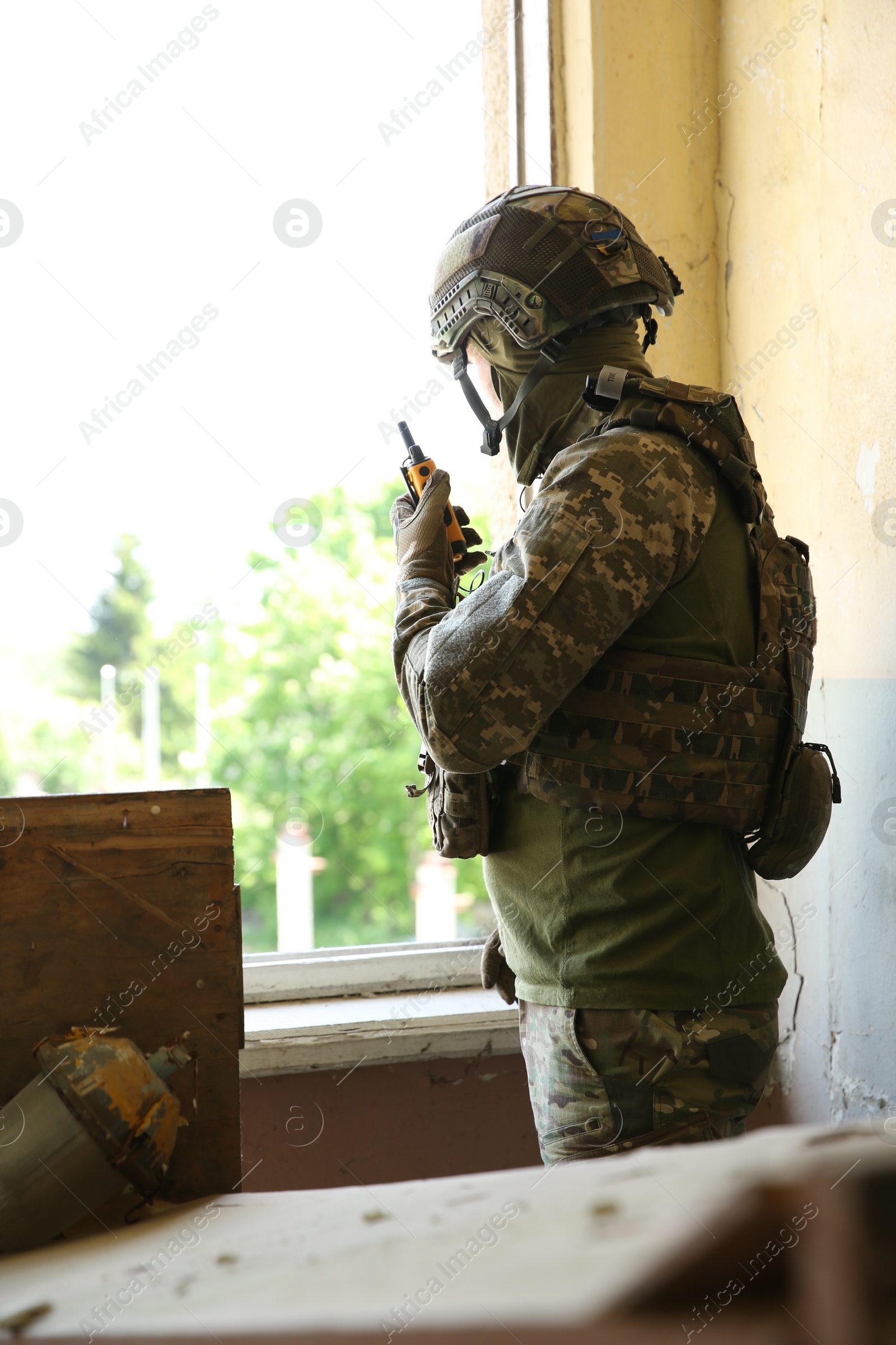 Photo of Military mission. Soldier in uniform with radio transmitter inside abandoned building