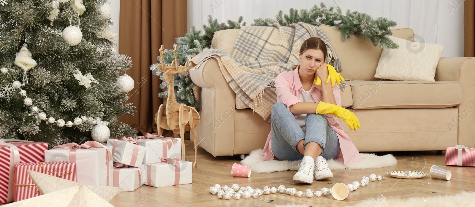 Image of Tired woman sitting in messy room while cleaning after New Year party. Banner design