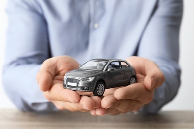 Photo of Male insurance agent holding toy car, closeup