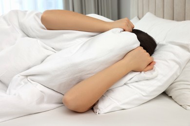 Photo of Woman covering head with blanket in bed at home