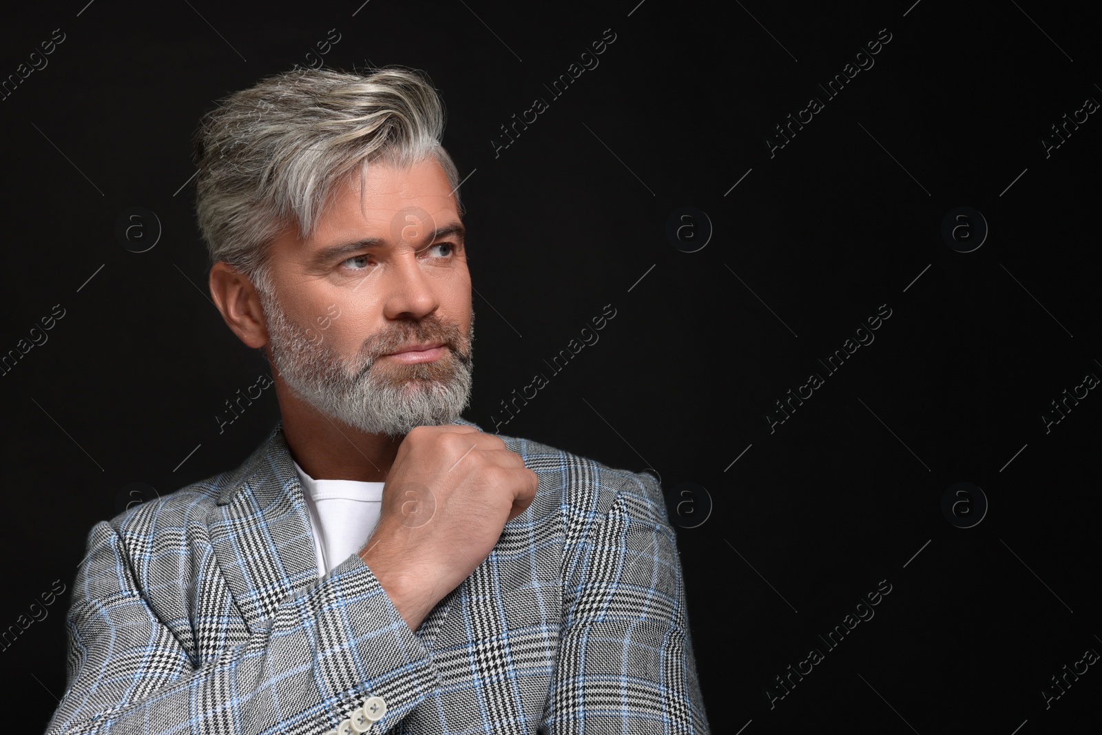 Photo of Portrait of confident man with beautiful hairstyle on black background. Space for text