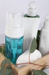 Different face cleansing products, cotton pads and eucalyptus leaves on table, closeup