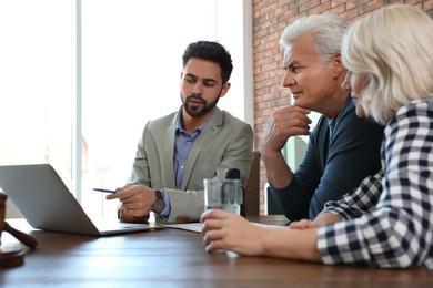 Photo of Male notary working with mature couple in office