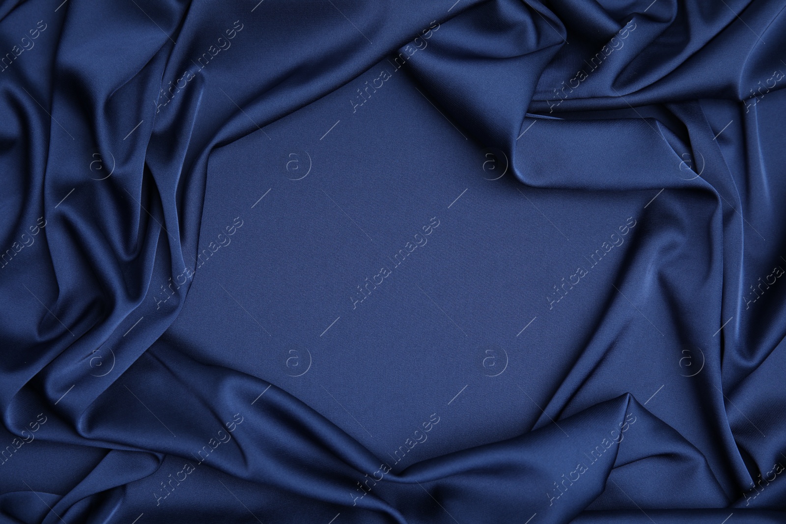 Photo of Crumpled dark blue silk fabric as background, top view. Space for text