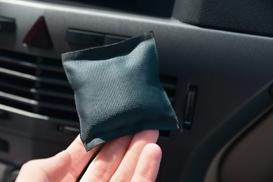 Woman with car air freshener in automobile, closeup