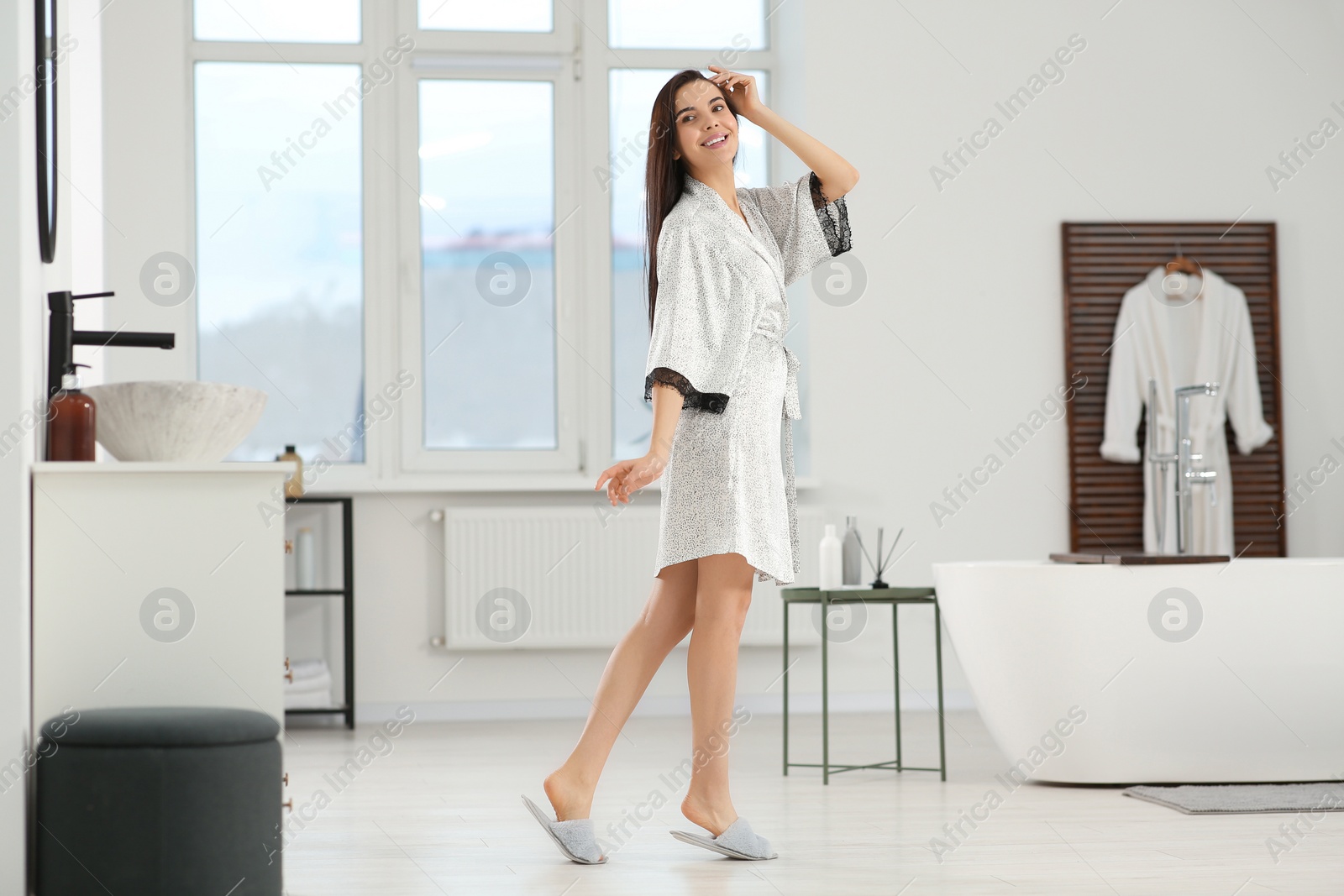 Photo of Beautiful happy woman wearing stylish bathrobe in bathroom