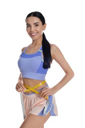 Young woman measuring waist with tape on white background