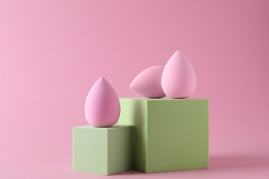 Photo of Stylish presentation of makeup sponges on pink background