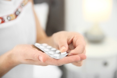 Young woman holding blister with pills, closeup