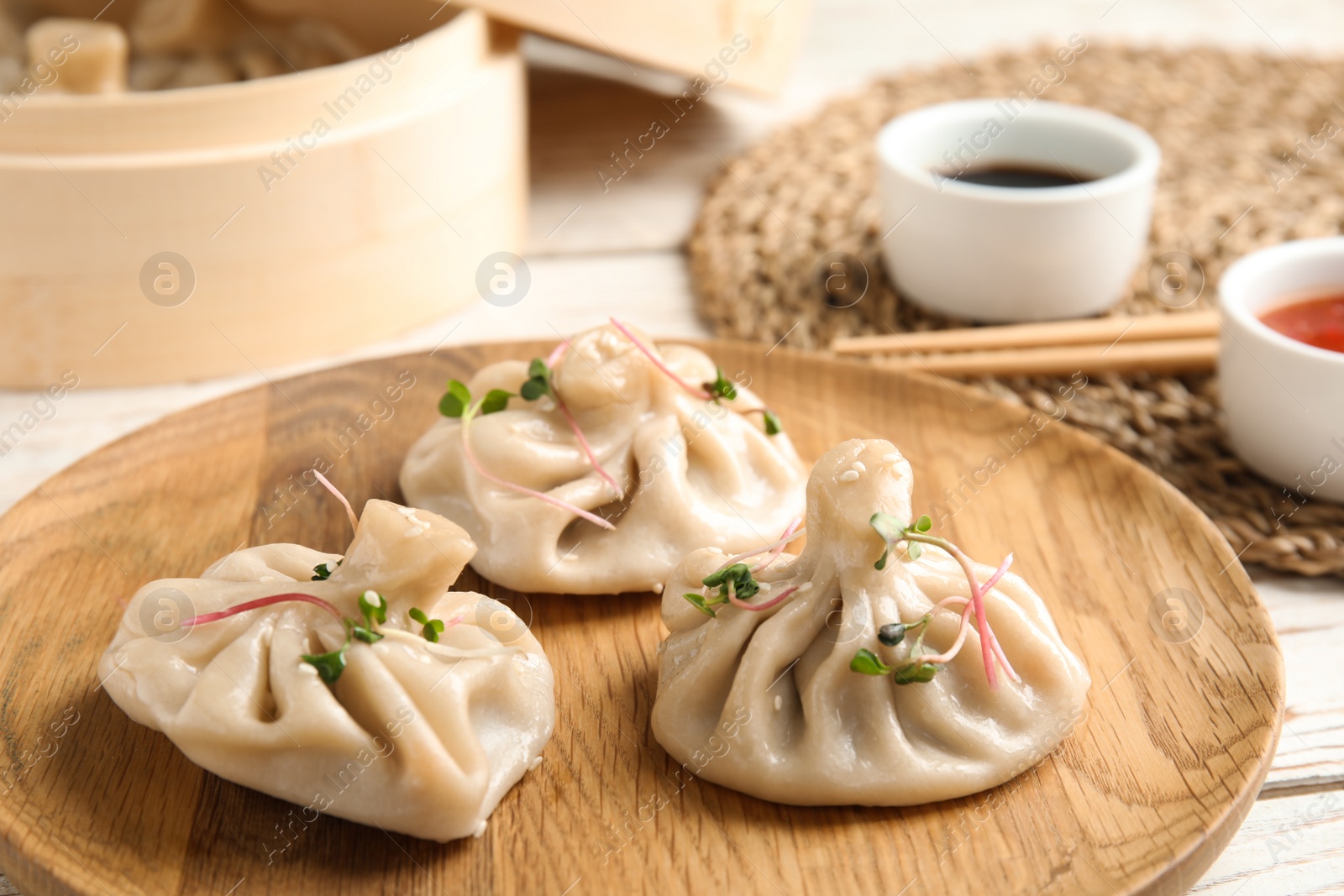 Photo of Wooden plate with tasty baozi dumplings on table, closeup