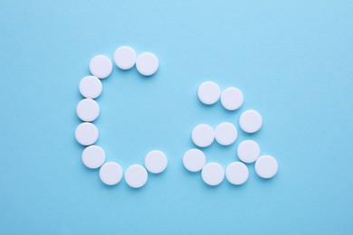Photo of Calcium symbol made of white pills on light blue background, flat lay