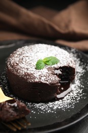 Delicious fresh fondant with hot chocolate and mint on black table, closeup