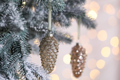 Photo of Christmas tree decorated with holiday baubles against blurred lights, closeup