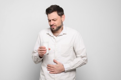 Man with glass of milk suffering from lactose intolerance on white background