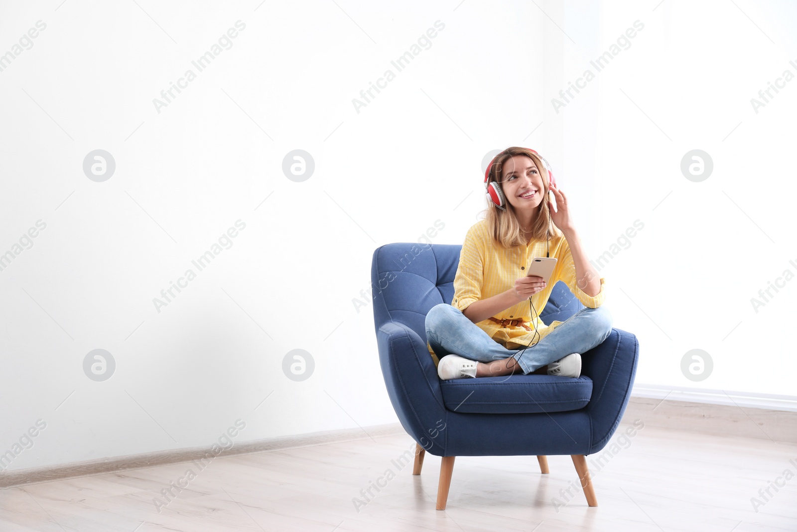 Photo of Young woman listening to music in armchair at home. Space for text