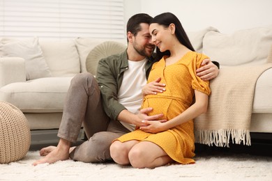 Happy pregnant woman spending time with her husband at home