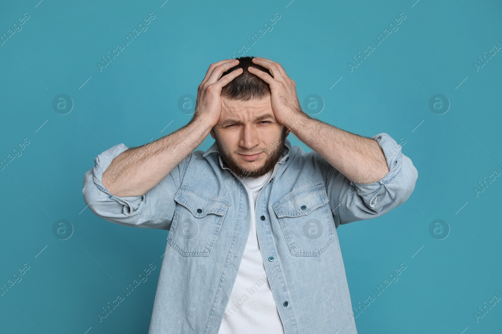 Photo of Man suffering from headache on light blue background