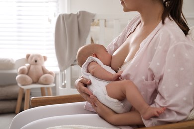 Photo of Young woman breastfeeding her little baby at home, closeup. Space for text