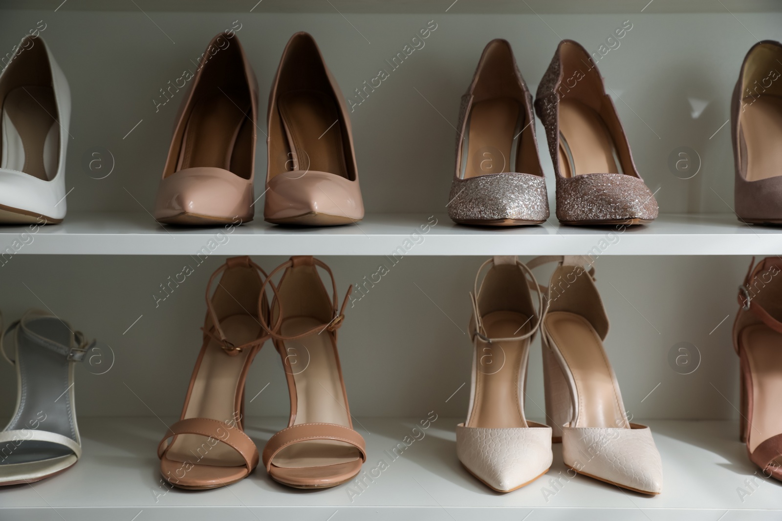 Photo of Different stylish women's shoes on shelving unit