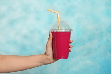 Photo of Woman holding plastic cup with delicious smoothie on color background