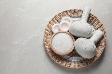 Photo of Composition with herbal massage bags and other spa products on light grey marble table, top view. Space for text