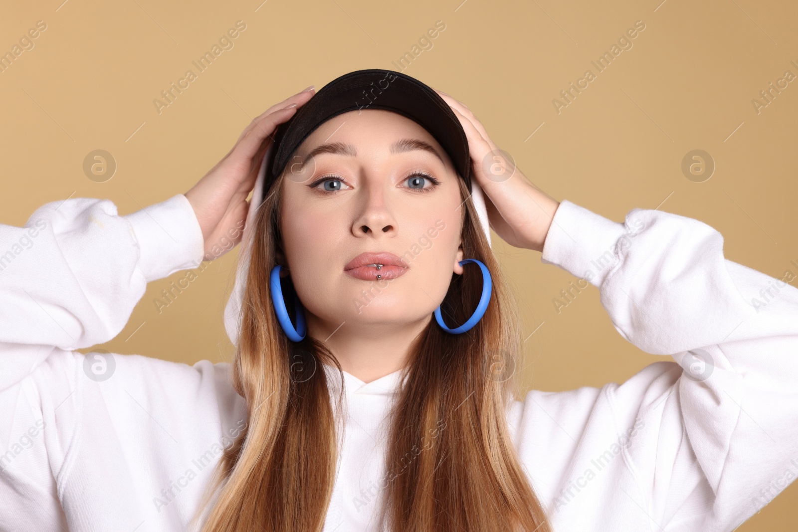 Photo of Young woman with lip piercing on beige background