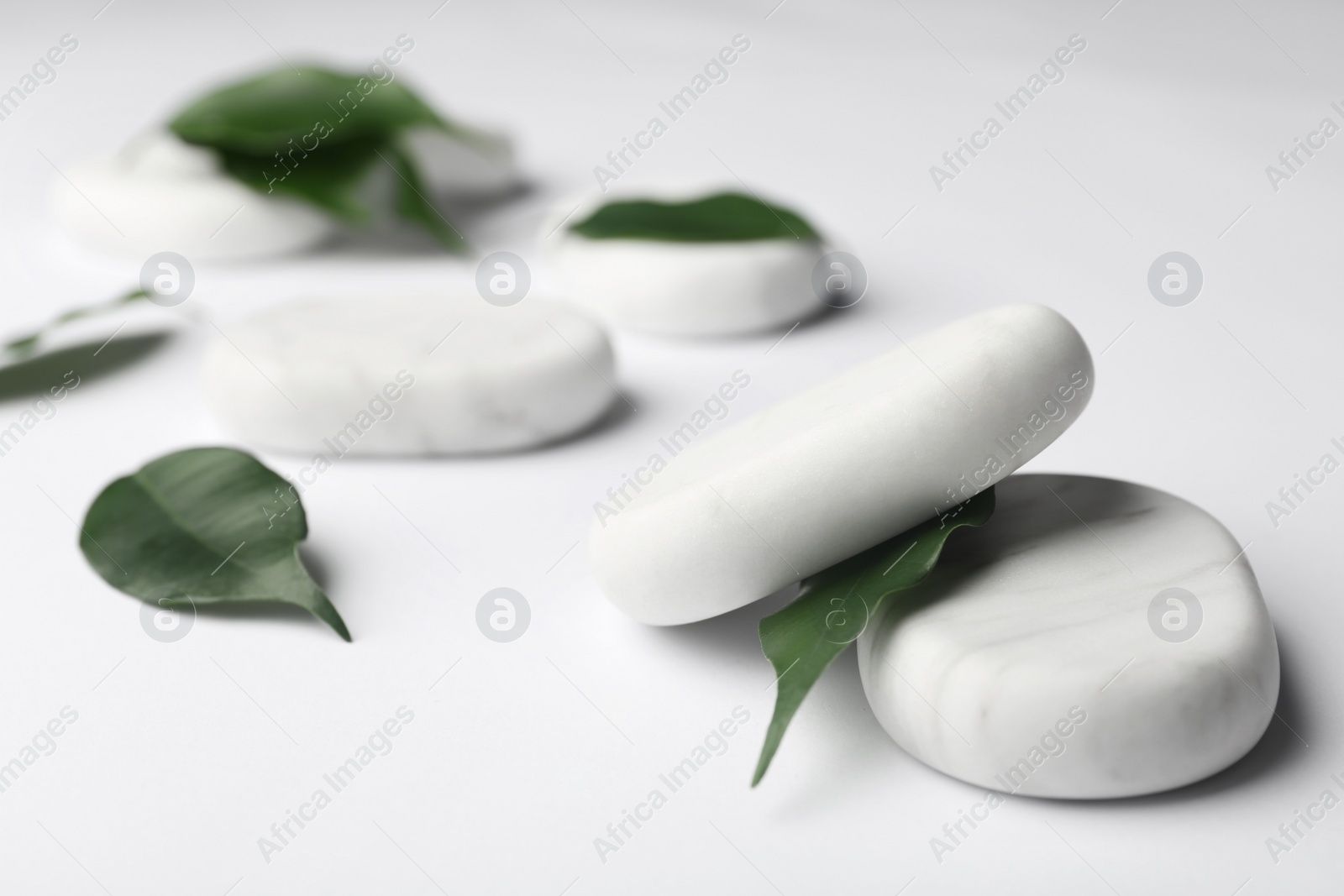 Photo of Spa stones and green leaves on white background. Space for text