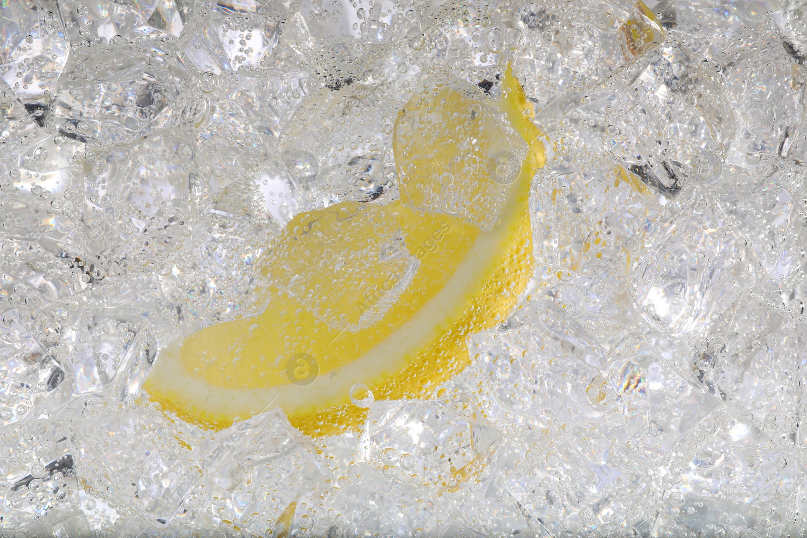 Photo of Juicy lemon slice and ice cubes in soda water against white background, closeup