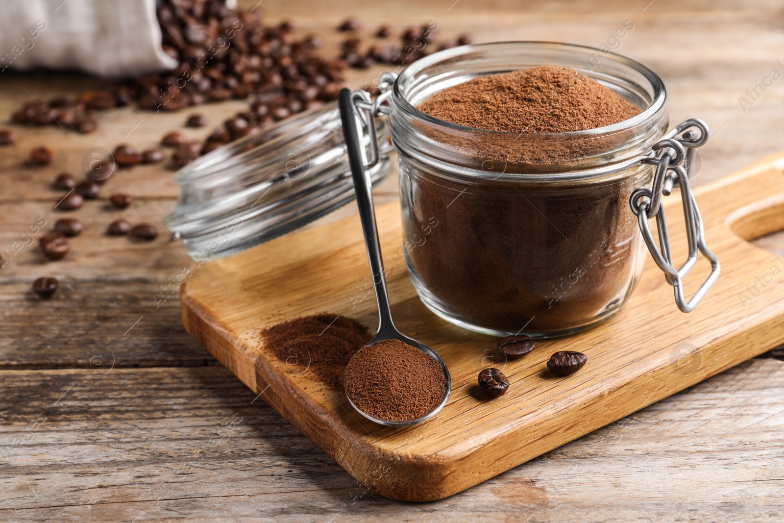 Photo of Glass jar of instant coffee and spoon on wooden table, closeup
