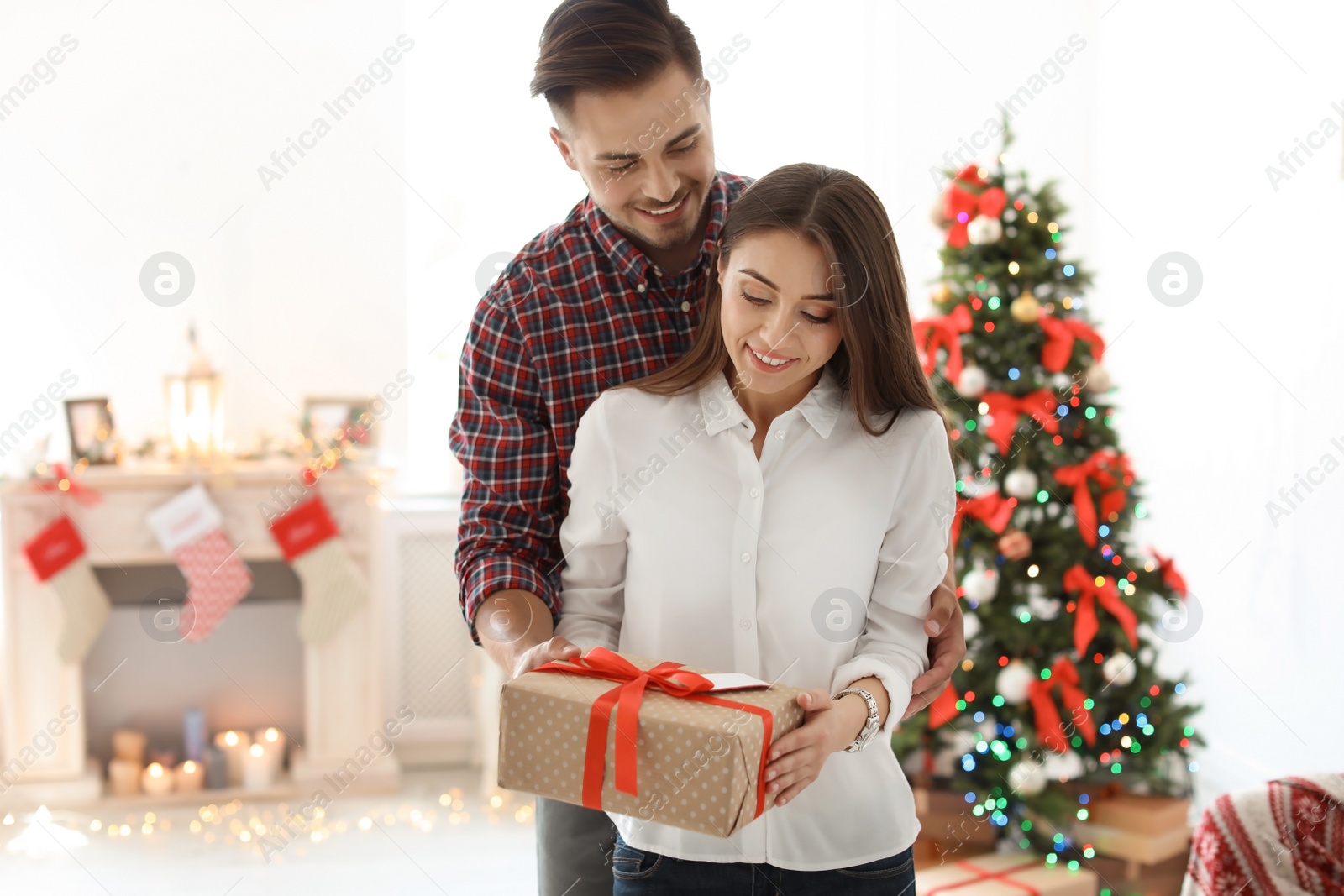 Photo of Young couple with Christmas gift at home