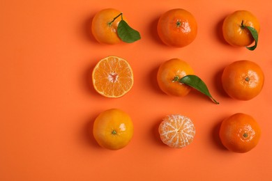 Delicious tangerines and green leaves on orange background, flat lay. Space for text