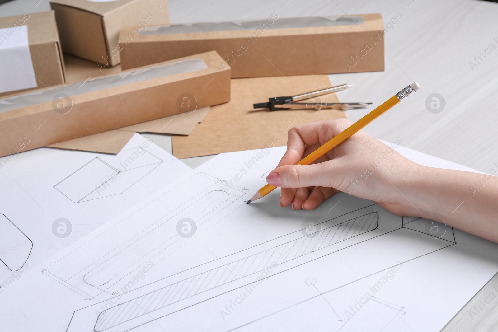 Photo of Woman creating packaging design at light wooden table, closeup