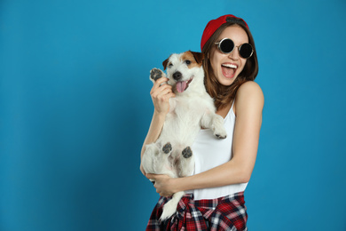 Young woman with her cute Jack Russell Terrier on light blue background. Lovely pet