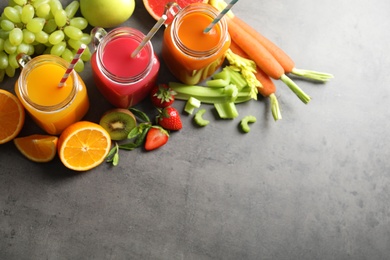 Different juices in mason jars and fresh ingredients on grey background, top view. Space for text