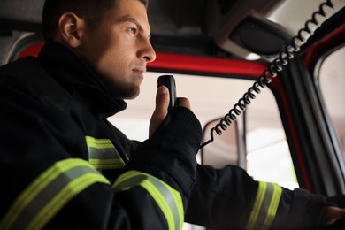 Photo of Firefighter using radio set while driving fire truck, closeup
